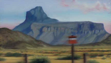 A distant blue-grey flat-topped mountain rises beyond scrubland, with blurred fence posts and a red sign in the foreground.