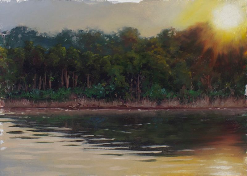 Sunset glows yellow through dark green lakeside trees, with warm light and shadow reflected across rippling water.