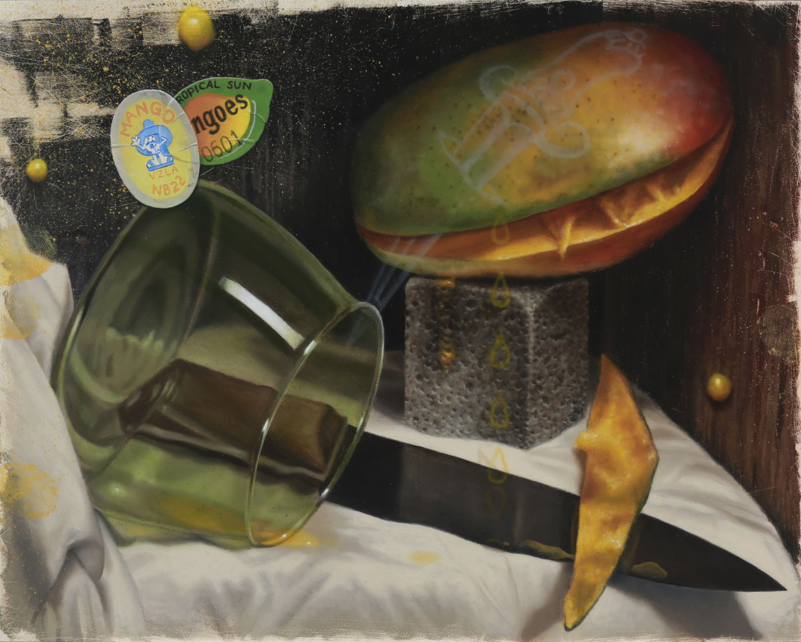 A mango rests on a stone block beside a tipped green glass, kitchen knife, curling peel, and fruit stickers.