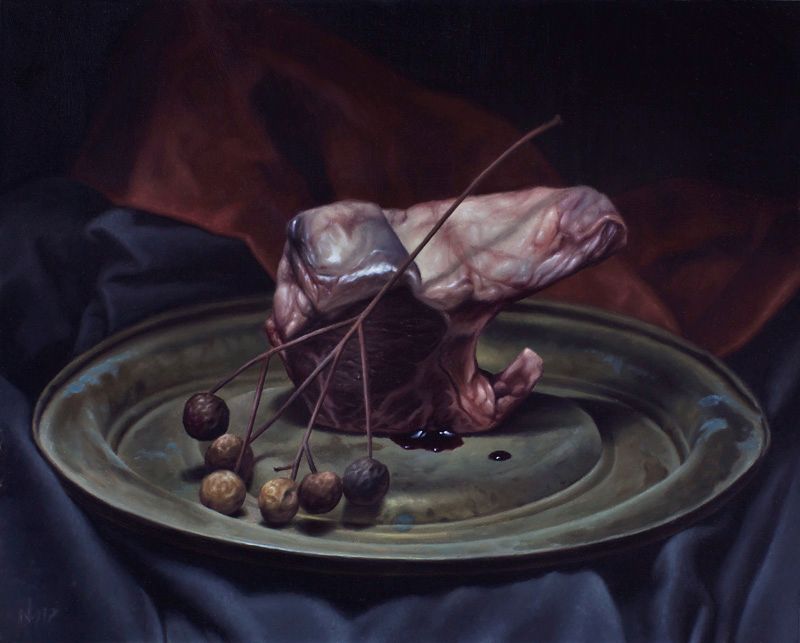 A raw mutton chop with dried berries on a green platter, surrounded by folds of dark blue and reddish-brown cloth.