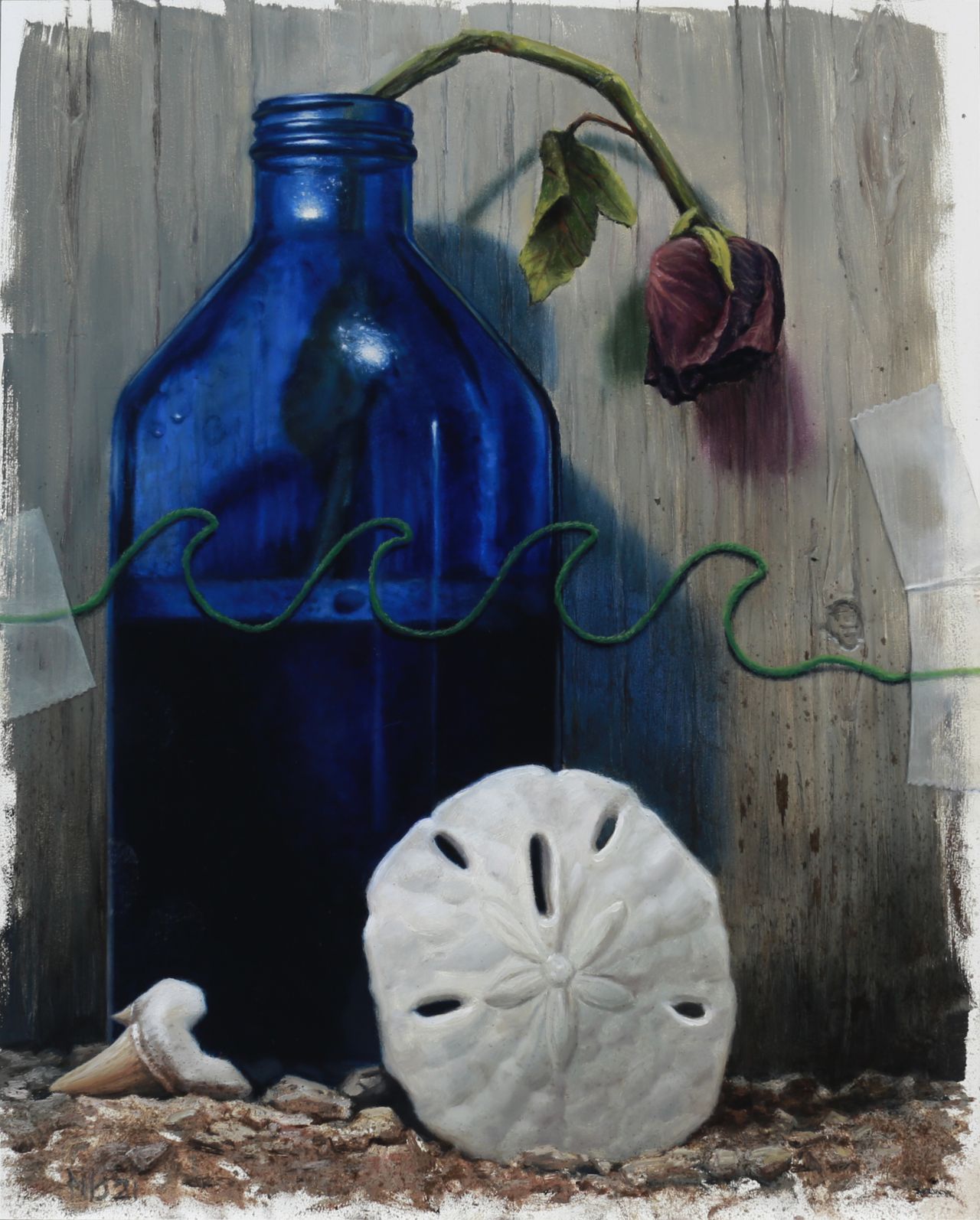 A cobalt-blue bottle, wilted purple rose, green wave-like cord, white sand dollar, and shark tooth rest against a gray wooden backdrop.