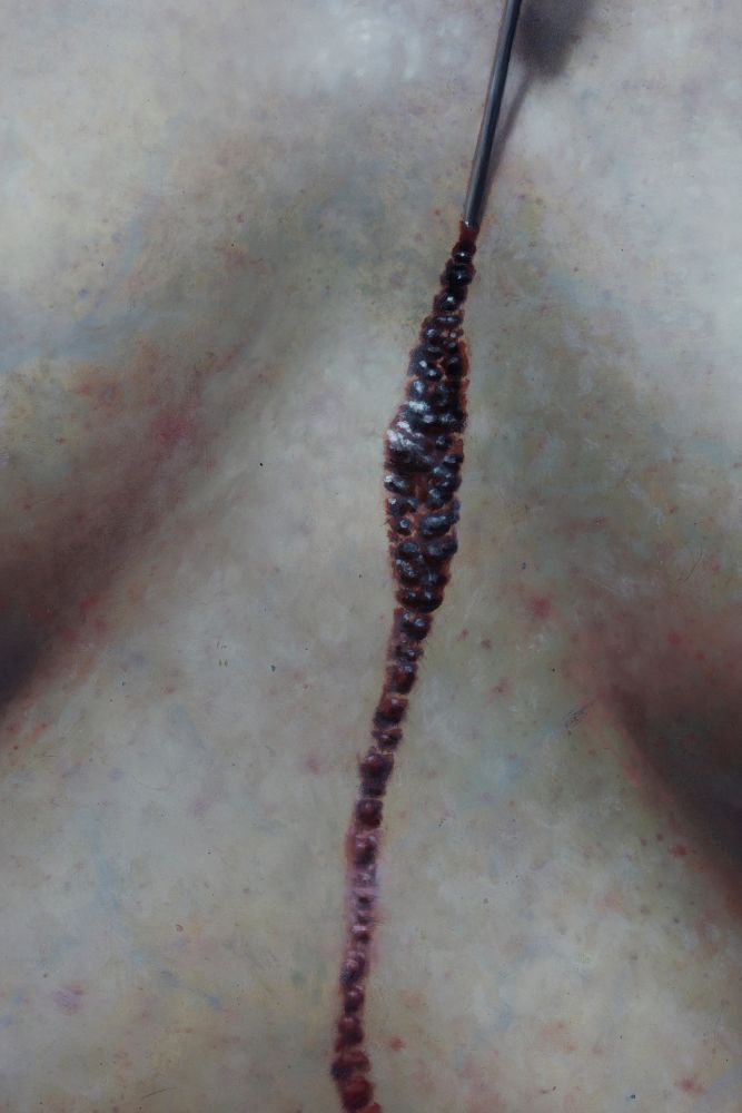 Extreme close up of female torso and sternum with dried blood drip falling vertically down the center.
