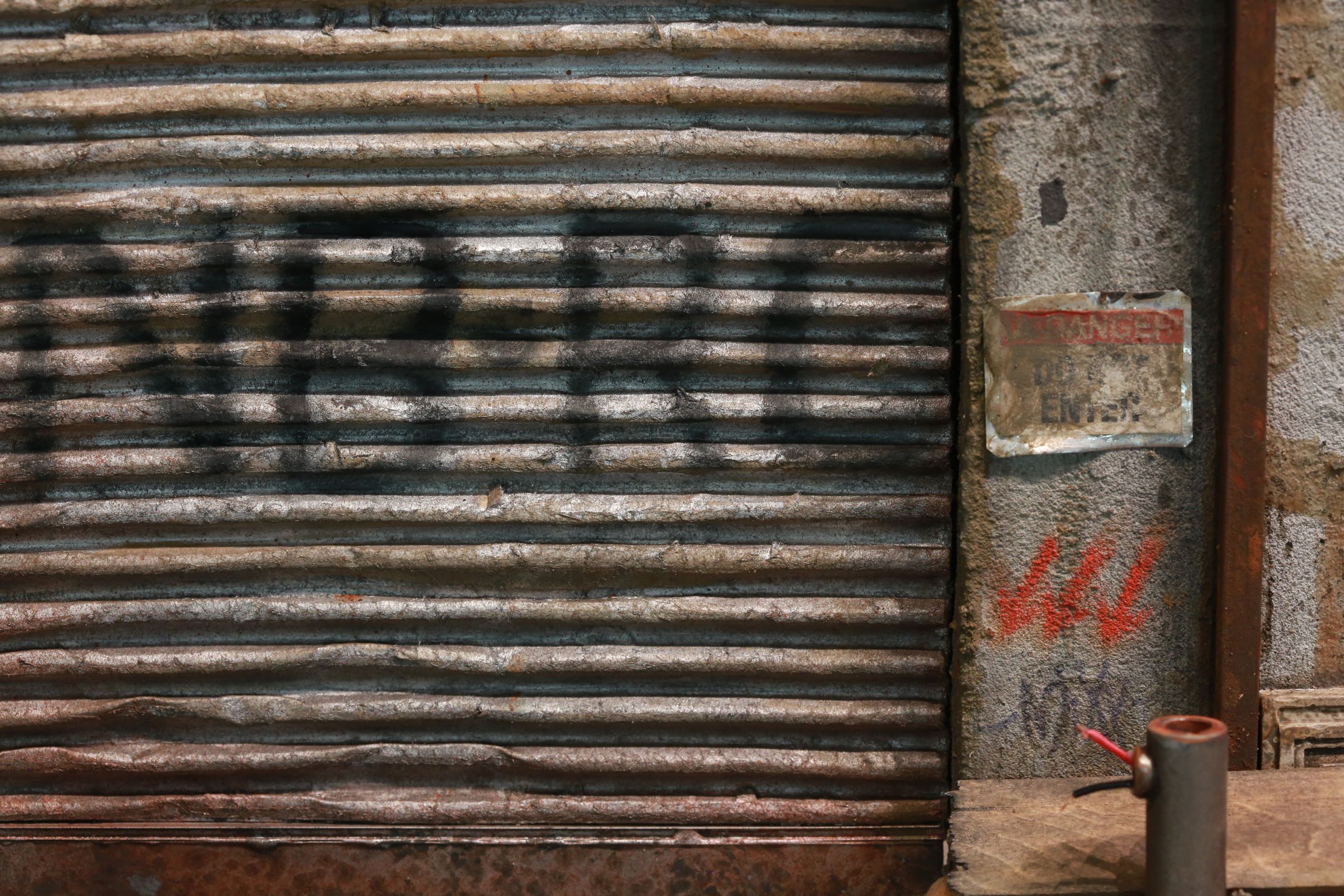 1/24-1/18 scale miniature diorama of a bombed out post apocalyptic inner city street alley way, with corrugated steel auto garage bay door, graffiti mural, and Frank Lloyd Wright Ennis House tiles