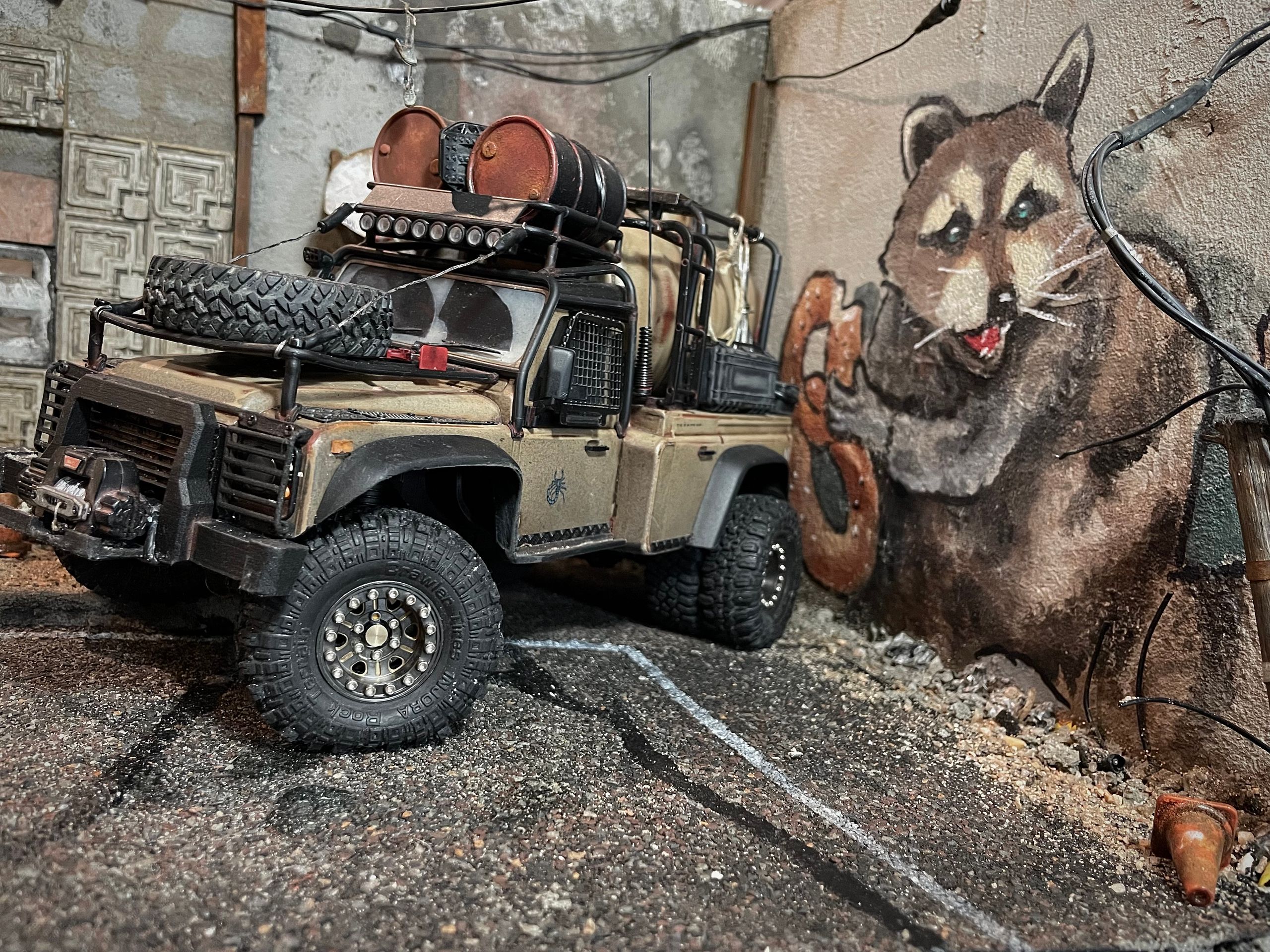 1/24-1/18 scale miniature diorama of a bombed out post apocalyptic inner city street alley way, with corrugated steel auto garage bay door, graffiti mural, and Frank Lloyd Wright Ennis House tiles