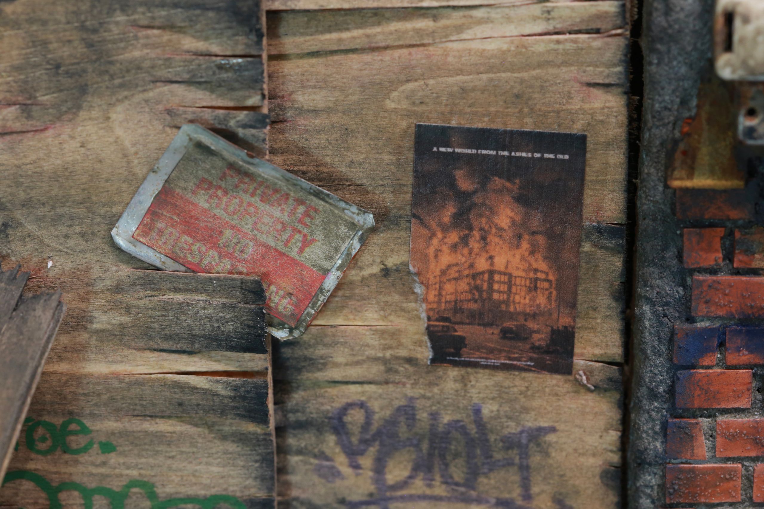 1/24-1/18 scale miniature diorama of a bombed out post apocalyptic inner city street alley way, with corrugated steel auto garage bay door, graffiti mural, and Frank Lloyd Wright Ennis House tiles
