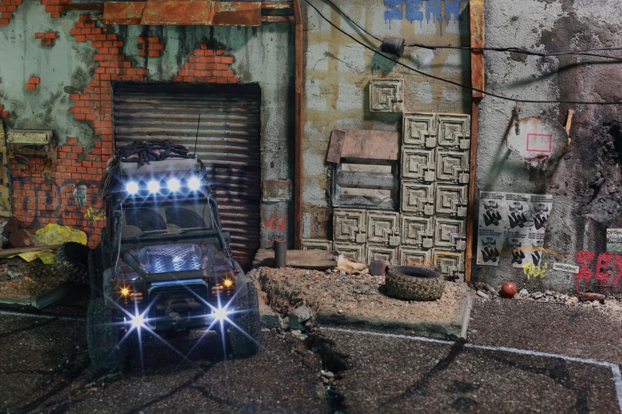 1/24-1/18 scale miniature diorama of a bombed out post apocalyptic inner city street alley way, with corrugated steel auto garage bay door, graffiti mural, and Frank Lloyd Wright Ennis House tiles