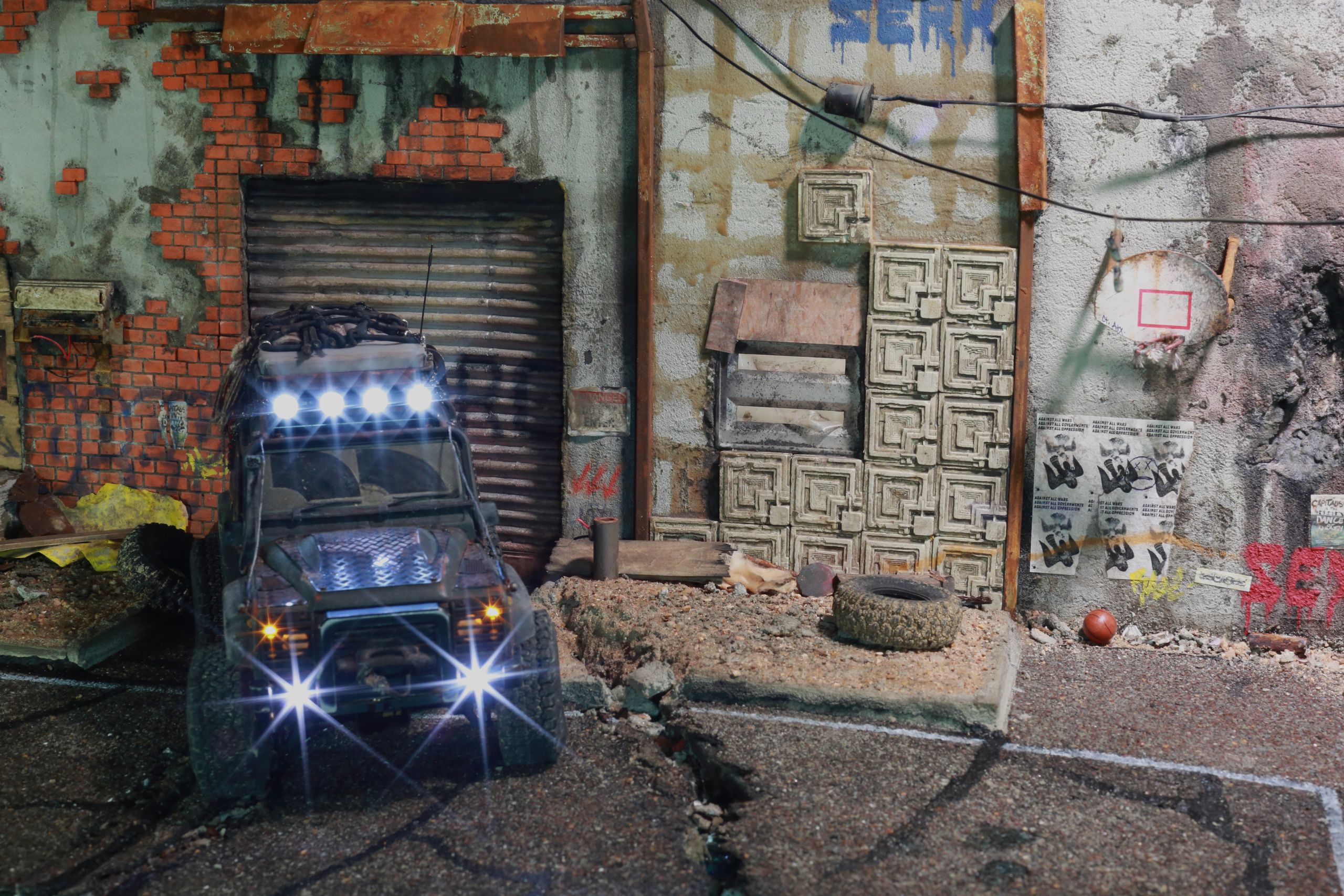 1/24-1/18 scale miniature diorama of a bombed out post apocalyptic inner city street alley way, with corrugated steel auto garage bay door, graffiti mural, and Frank Lloyd Wright Ennis House tiles