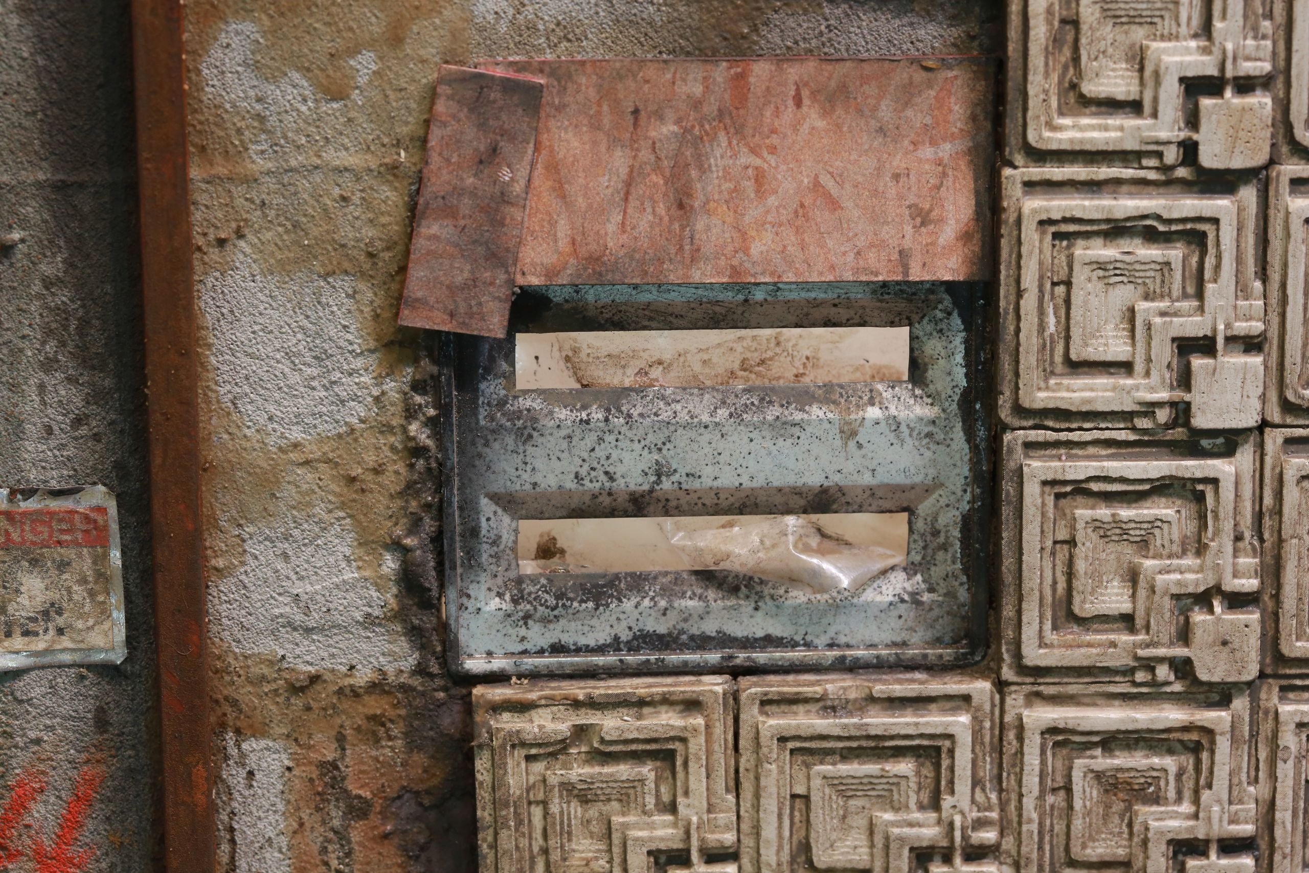 1/24-1/18 scale miniature diorama of a bombed out post apocalyptic inner city street alley way, with corrugated steel auto garage bay door, graffiti mural, and Frank Lloyd Wright Ennis House tiles