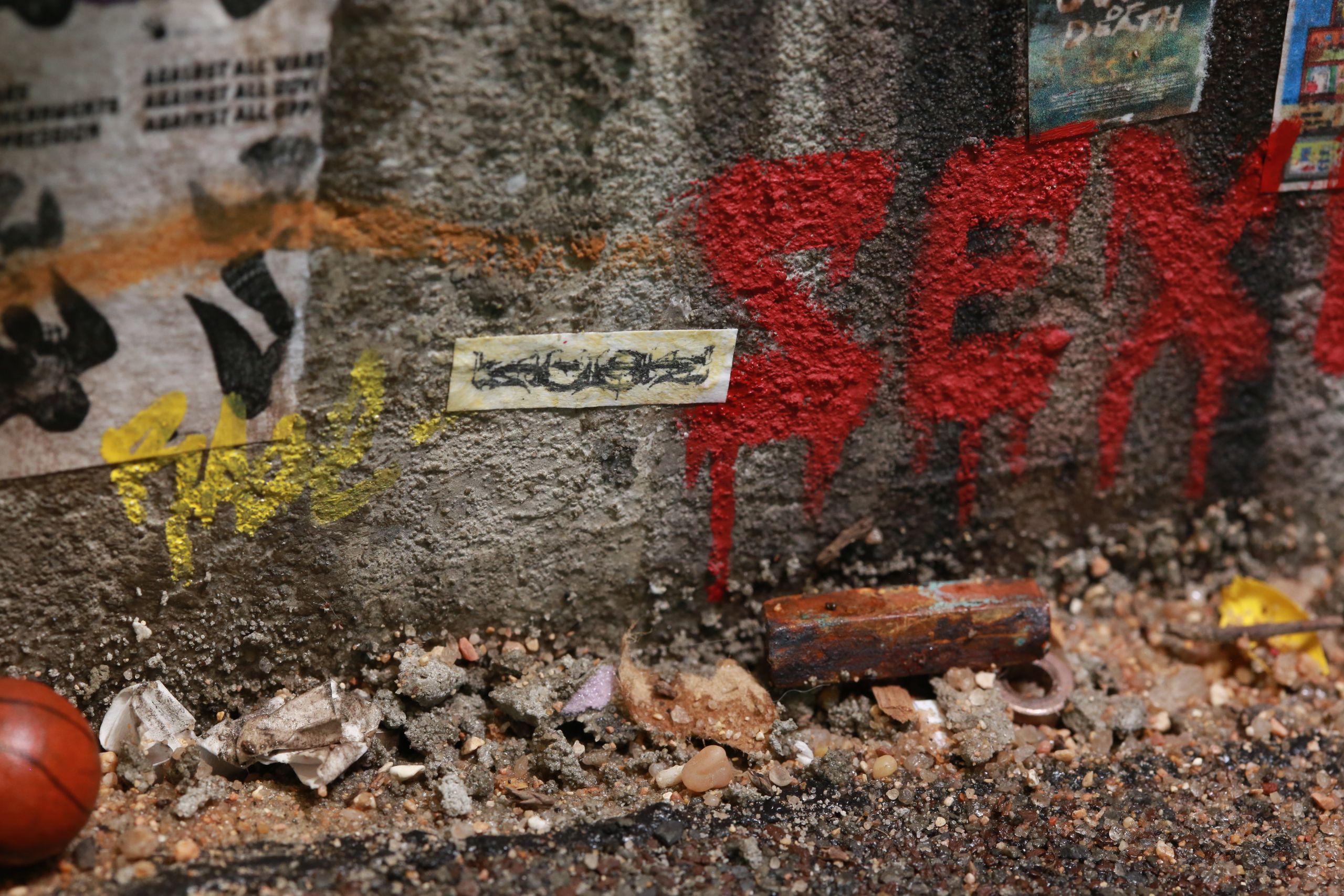 1/24-1/18 scale miniature diorama of a bombed out post apocalyptic inner city street alley way, with corrugated steel auto garage bay door, graffiti mural, and Frank Lloyd Wright Ennis House tiles