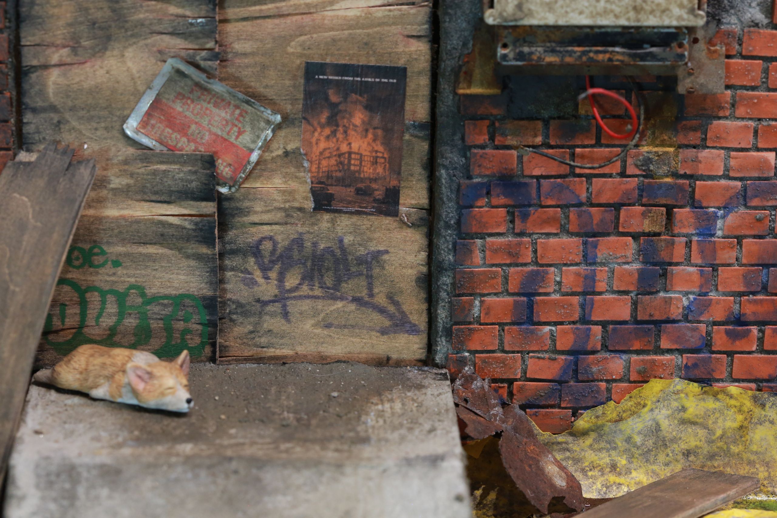 1/24-1/18 scale miniature diorama of a bombed out post apocalyptic inner city street alley way, with corrugated steel auto garage bay door, graffiti mural, and Frank Lloyd Wright Ennis House tiles