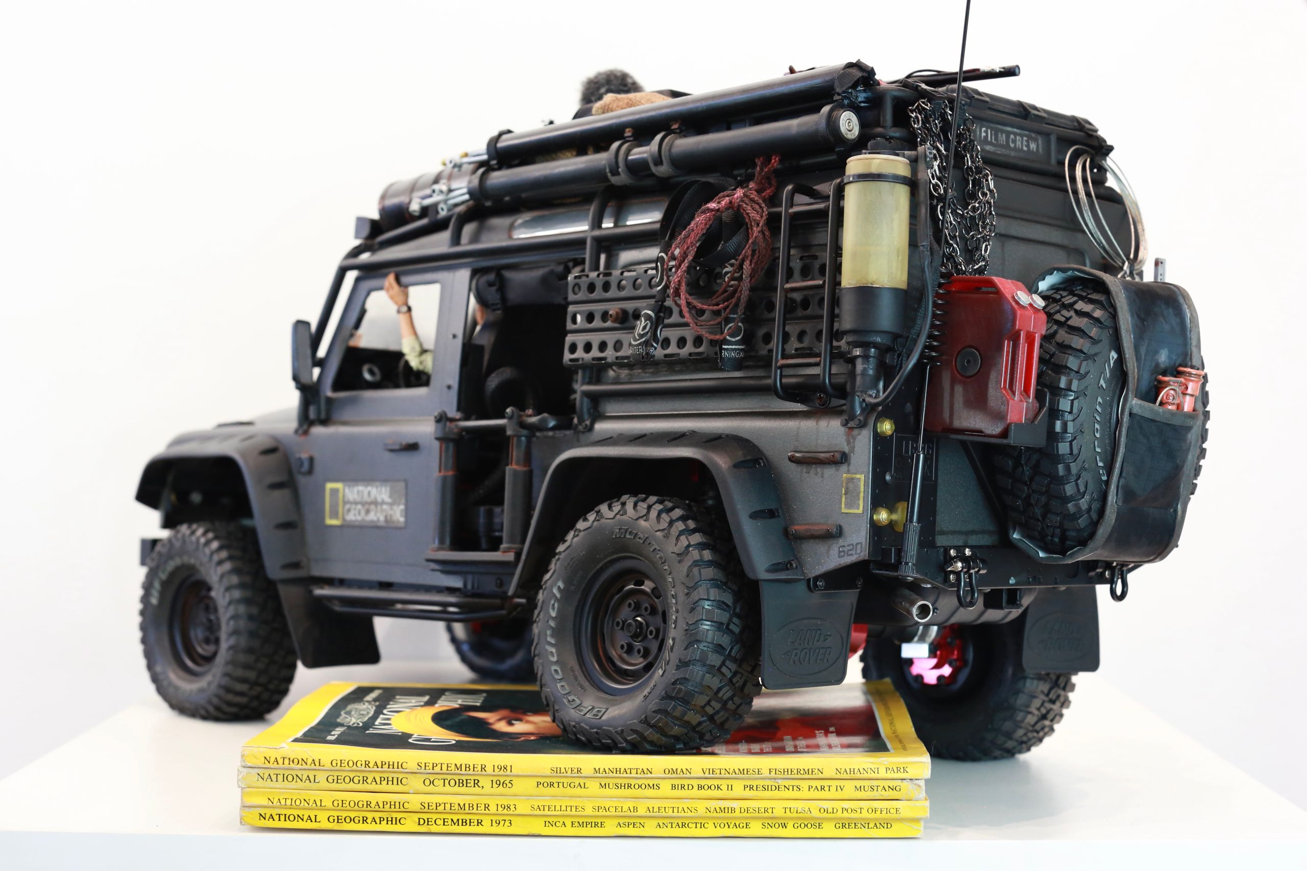 1/10 scale RC Defender 110 build inspired by the heavily modified and customized Land Rover Defenders used by National Geographic photographers in the 80s and 90s in places like the African savanna, featuring a custom cab interior and rear camera platforms, as well as many handmade accessories constructed from found objects and household junk.