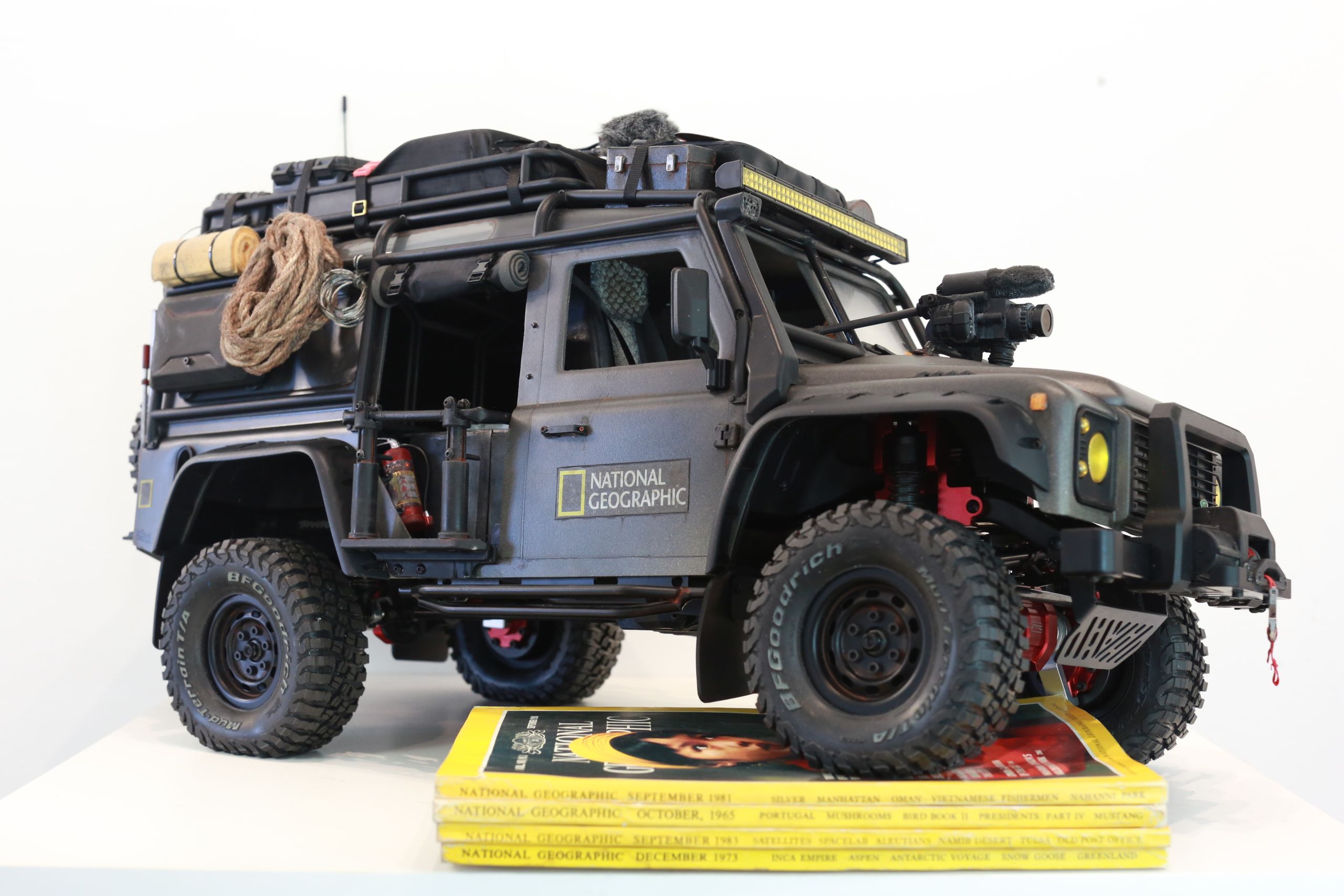 1/10 scale RC Defender 110 build inspired by the heavily modified and customized Land Rover Defenders used by National Geographic photographers in the 80s and 90s in places like the African savanna, featuring a custom cab interior and rear camera platforms, as well as many handmade accessories constructed from found objects and household junk.