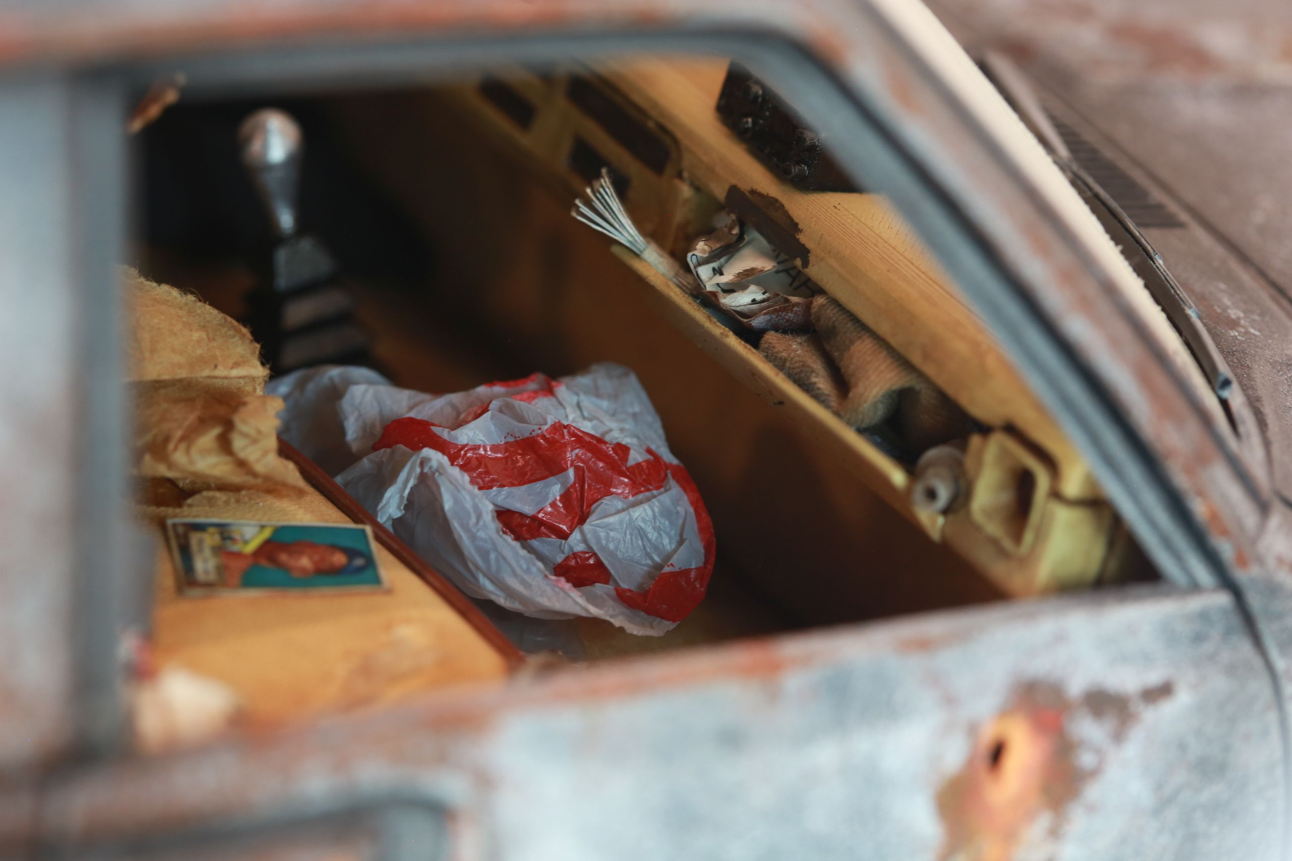 An old Toyota Hilux cab-only "beater" pickup truck working RC vehicle in 1/10 scale, with a gooseneck trailer hitch platform and carrying a spare wheel. Featuring a custom interior with action figure driver, handmade accessories, and faux leather bench seat.