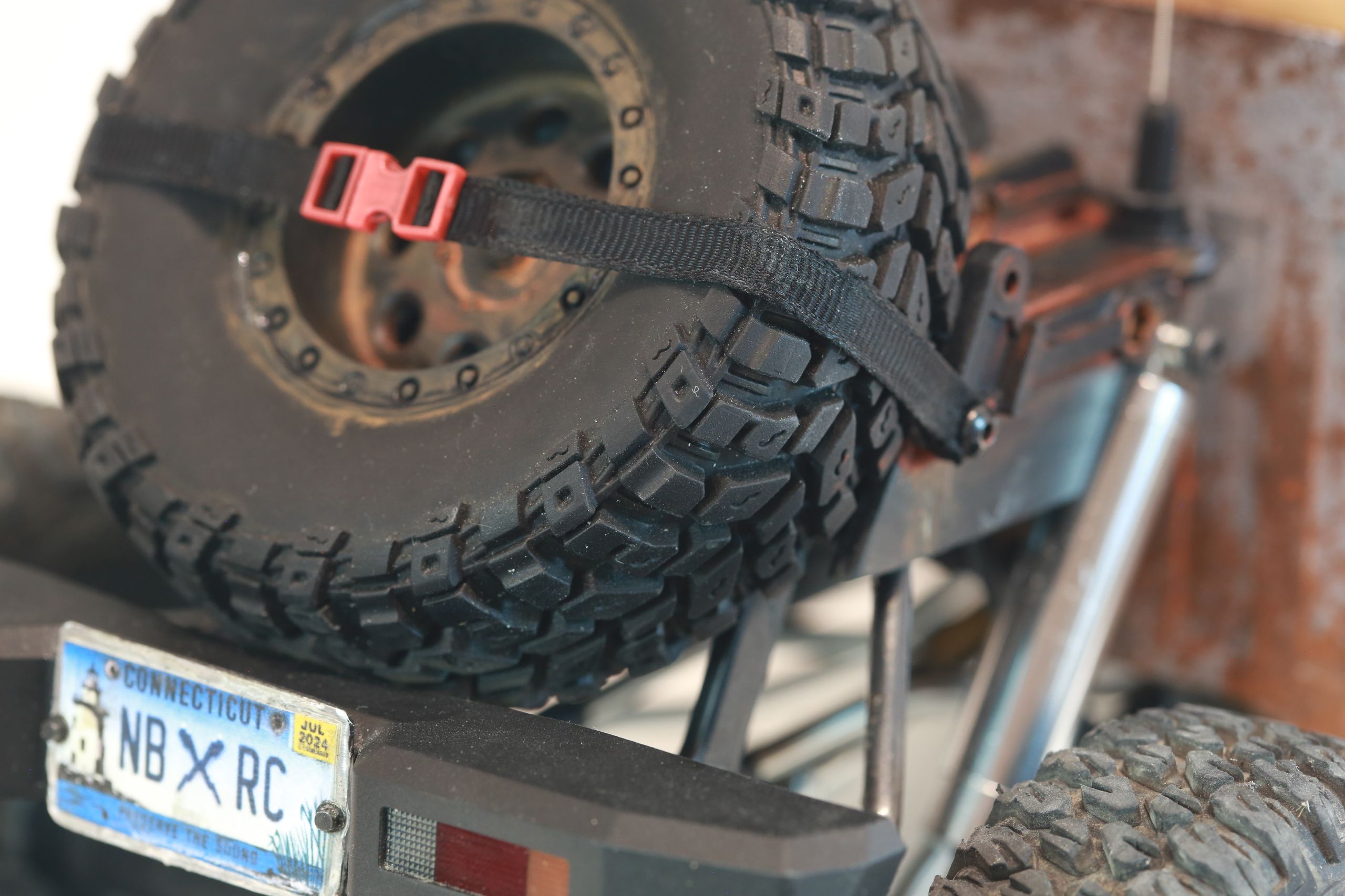 An old Toyota Hilux cab-only "beater" pickup truck working RC vehicle in 1/10 scale, with a gooseneck trailer hitch platform and carrying a spare wheel. Featuring a custom interior with action figure driver, handmade accessories, and faux leather bench seat.