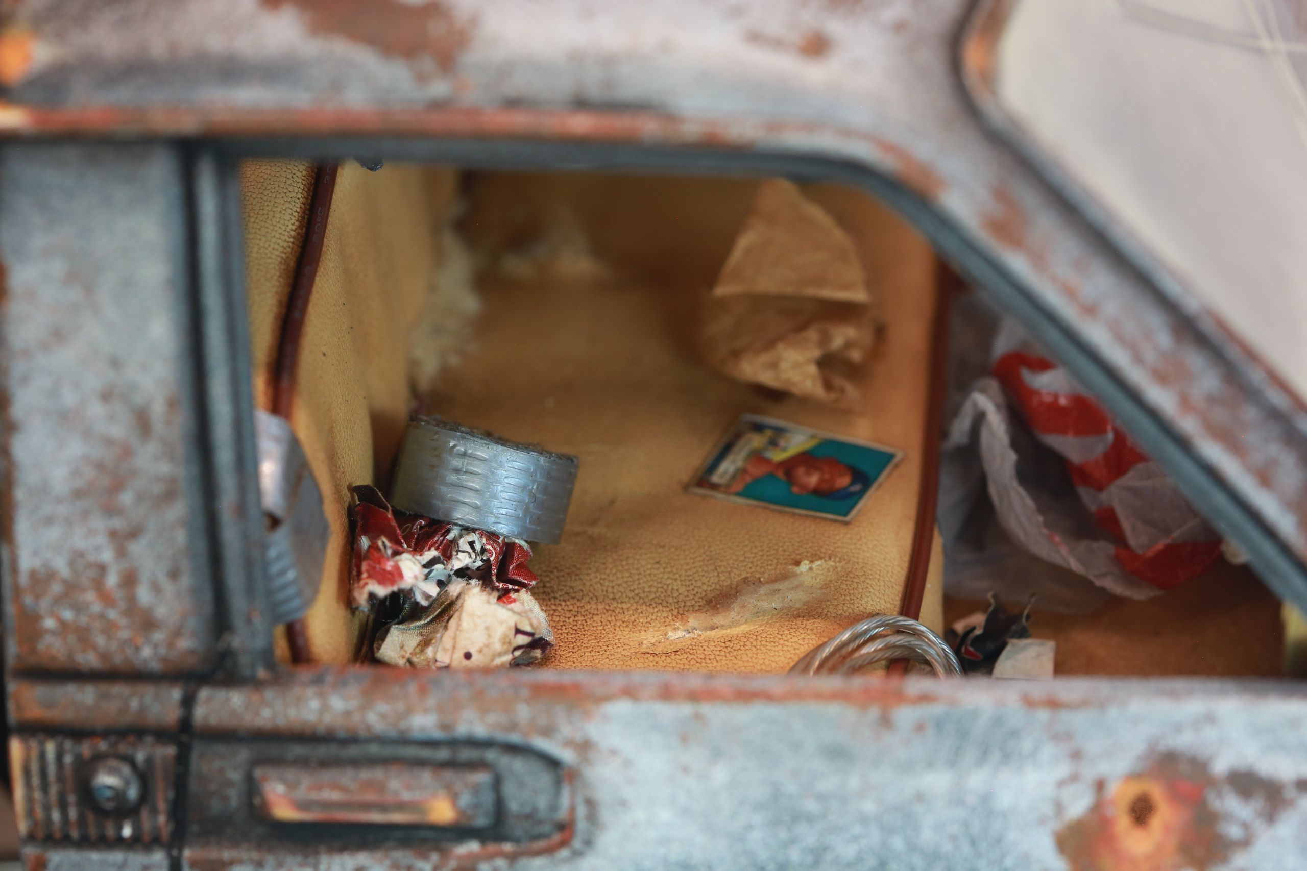 An old Toyota Hilux cab-only "beater" pickup truck working RC vehicle in 1/10 scale, with a gooseneck trailer hitch platform and carrying a spare wheel. Featuring a custom interior with action figure driver, handmade accessories, and faux leather bench seat.