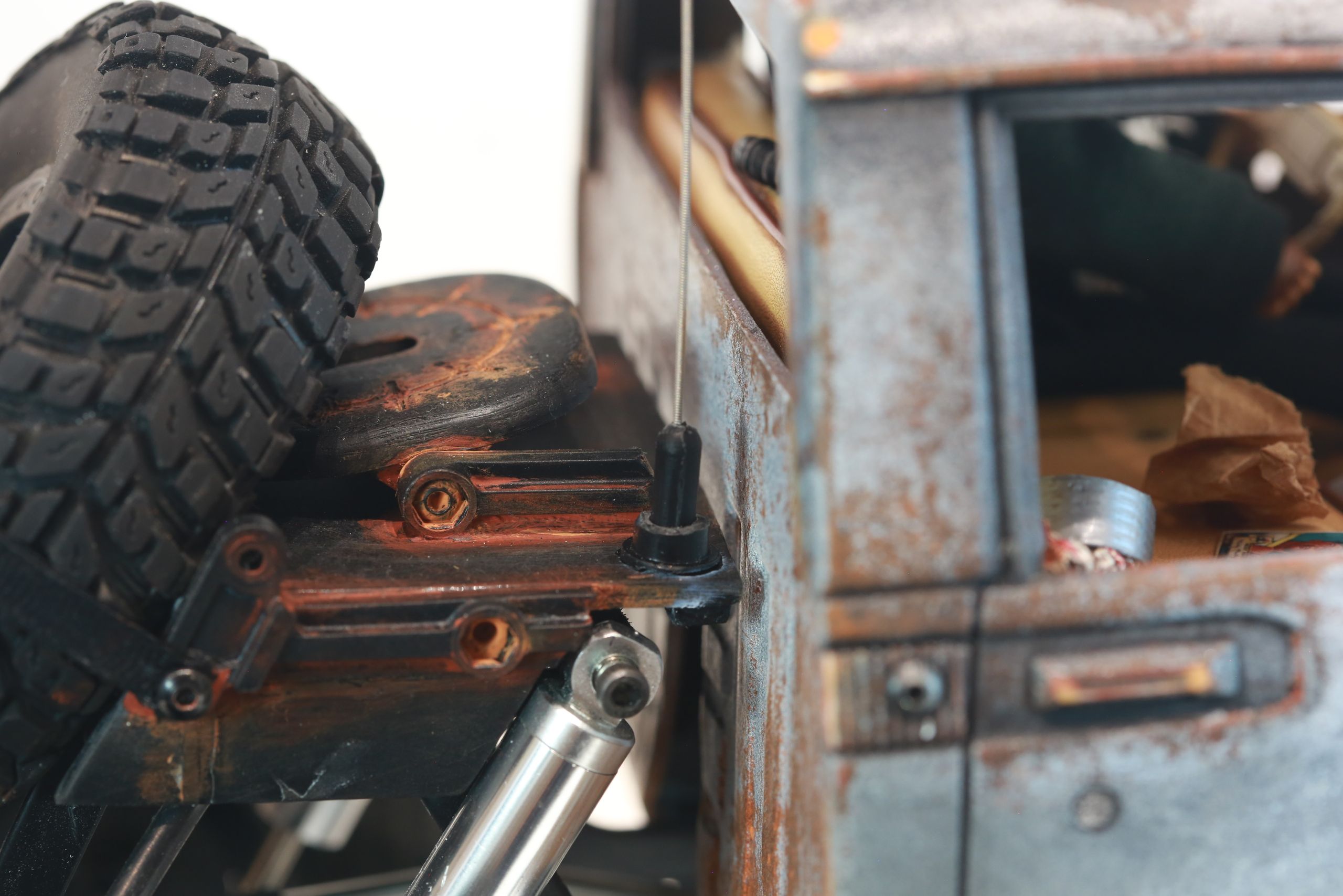 An old Toyota Hilux cab-only "beater" pickup truck working RC vehicle in 1/10 scale, with a gooseneck trailer hitch platform and carrying a spare wheel. Featuring a custom interior with action figure driver, handmade accessories, and faux leather bench seat.