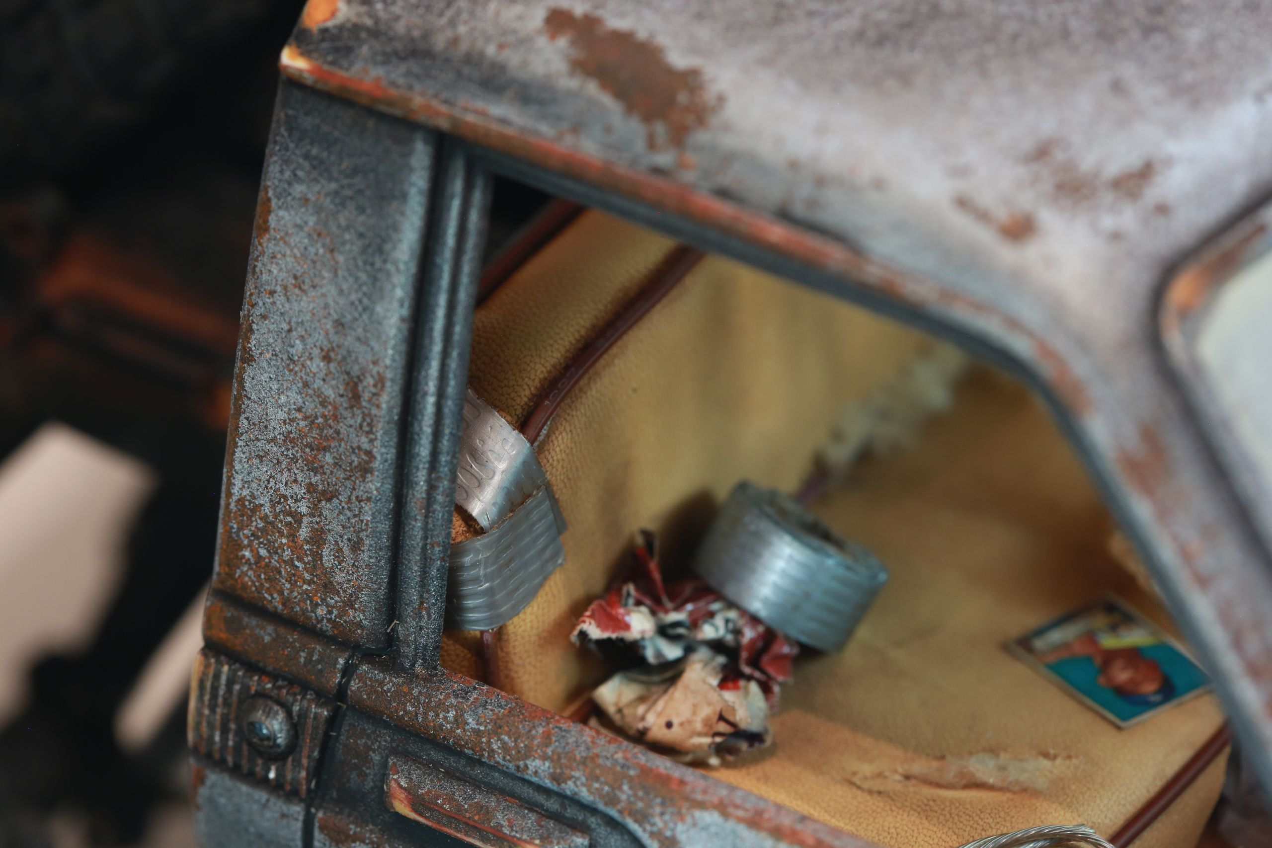 An old Toyota Hilux cab-only "beater" pickup truck working RC vehicle in 1/10 scale, with a gooseneck trailer hitch platform and carrying a spare wheel. Featuring a custom interior with action figure driver, handmade accessories, and faux leather bench seat.