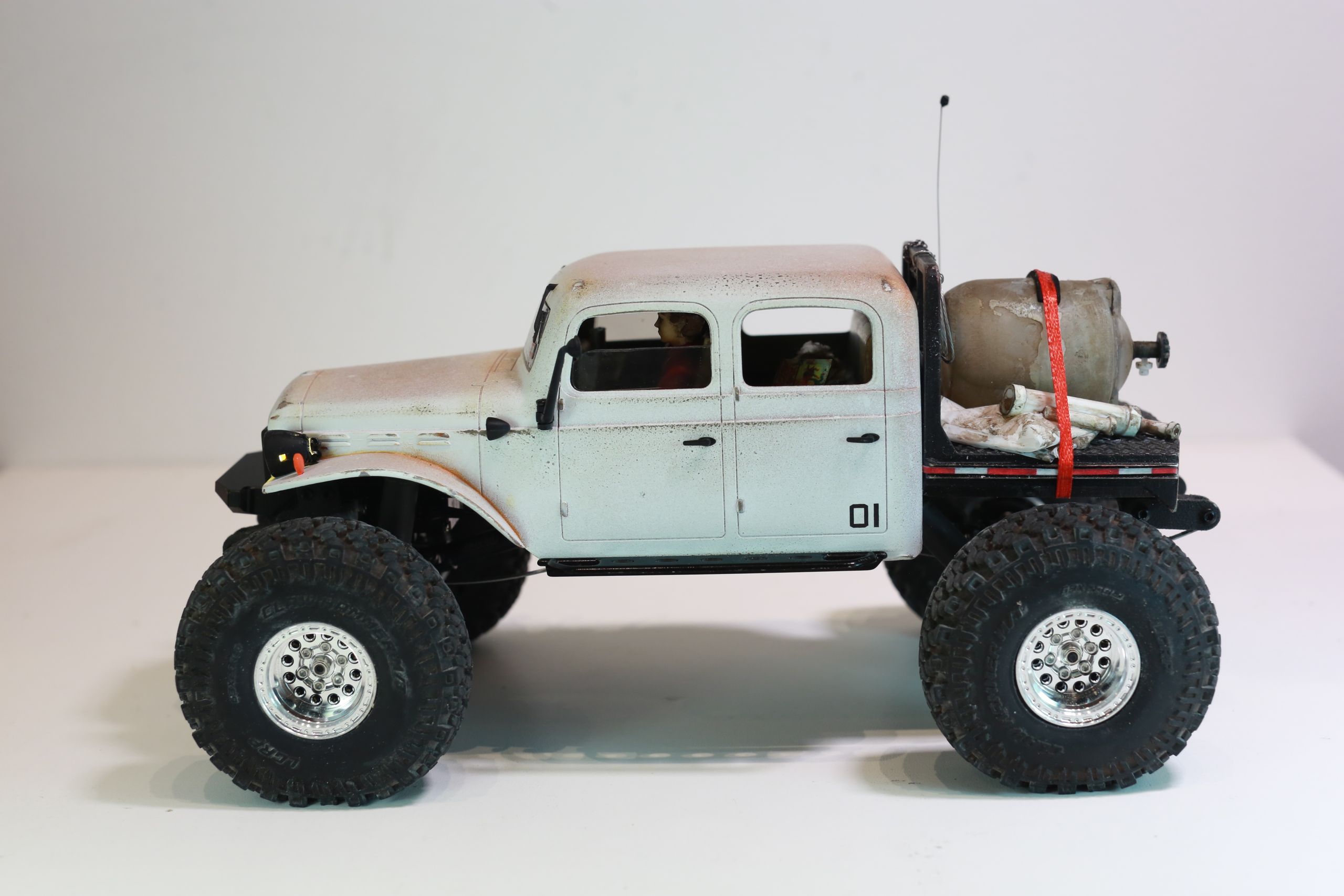1/24 scale 1950's Dodge Power Wagon RC truck by austin texas artist Nick Baxter with a flatbed hauling a potable water tank and industrial plumbing equipment, riding on a custom leaf spring suspension system designed and tuned by the artist