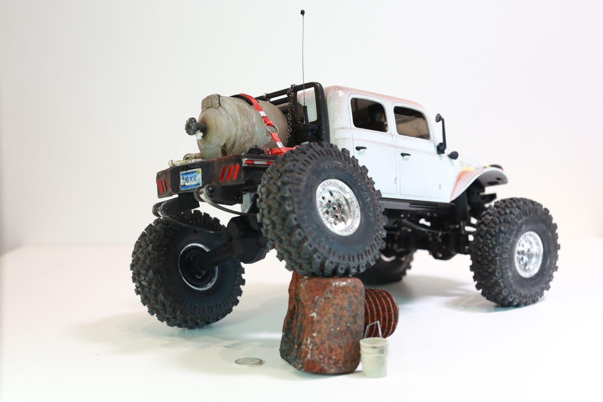 1/24 scale 1950's Dodge Power Wagon RC truck by austin texas artist Nick Baxter with a flatbed hauling a potable water tank and industrial plumbing equipment, riding on a custom leaf spring suspension system designed and tuned by the artist