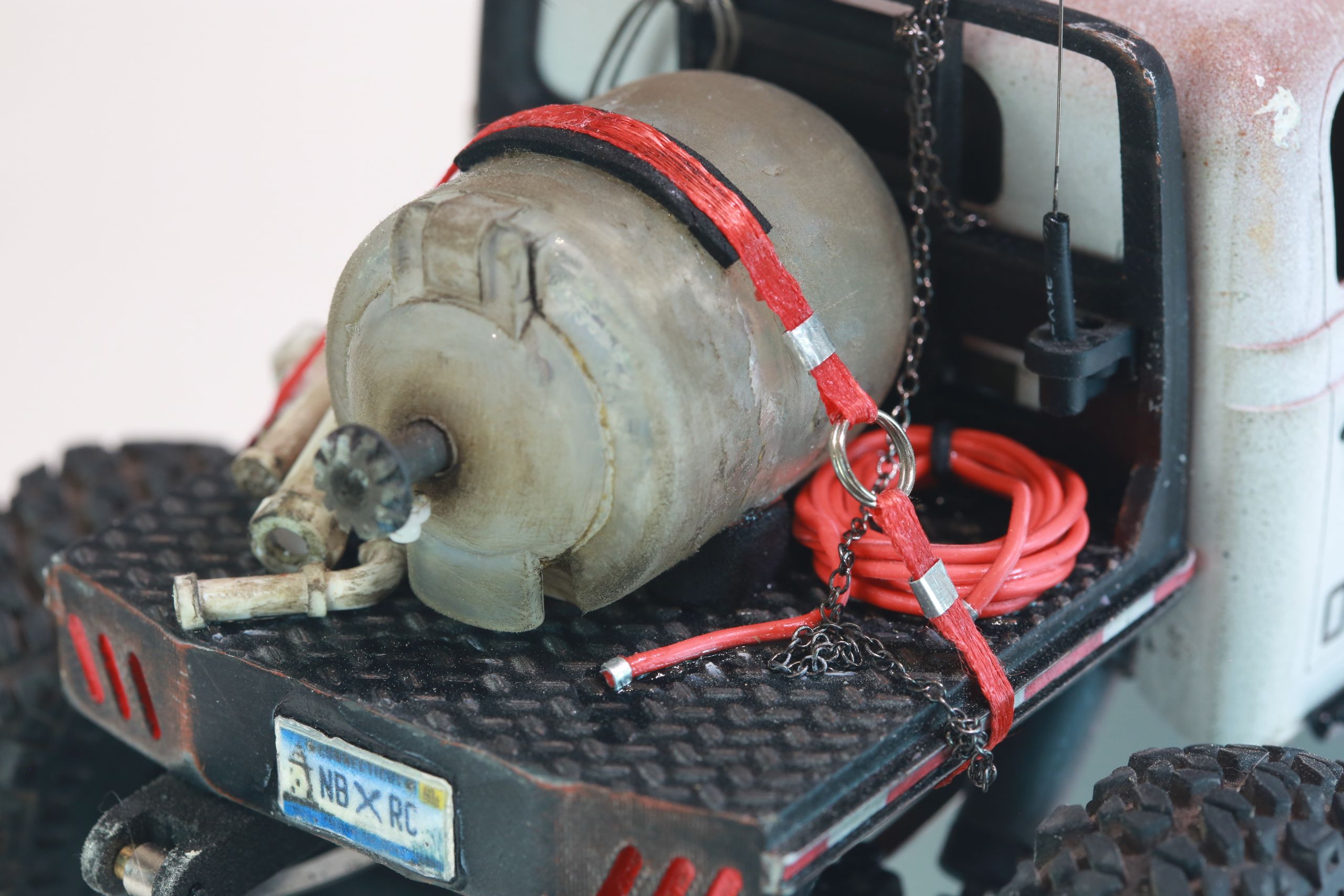 1/24 scale 1950's Dodge Power Wagon RC truck by austin texas artist Nick Baxter with a flatbed hauling a potable water tank and industrial plumbing equipment, riding on a custom leaf spring suspension system designed and tuned by the artist