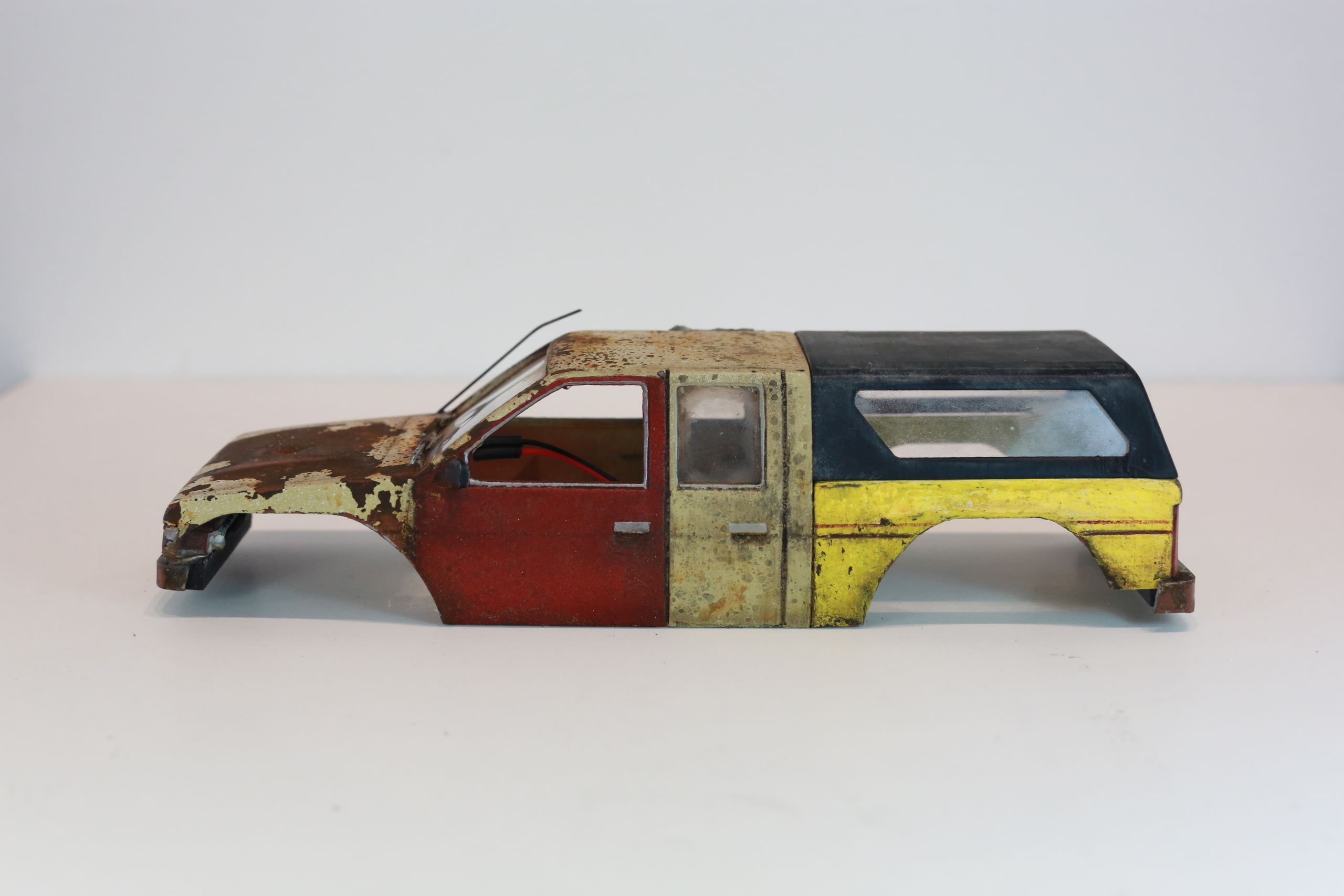 Old junkyard Nissan 1/24 scale 3d printed pickup body for scx24 RC truck with real rust patina, dents, duct tape windows, and custom bumpers.