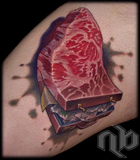 view of a small color tattoo of raw steak meat turning into a brown briefcase with business papers spilling out.