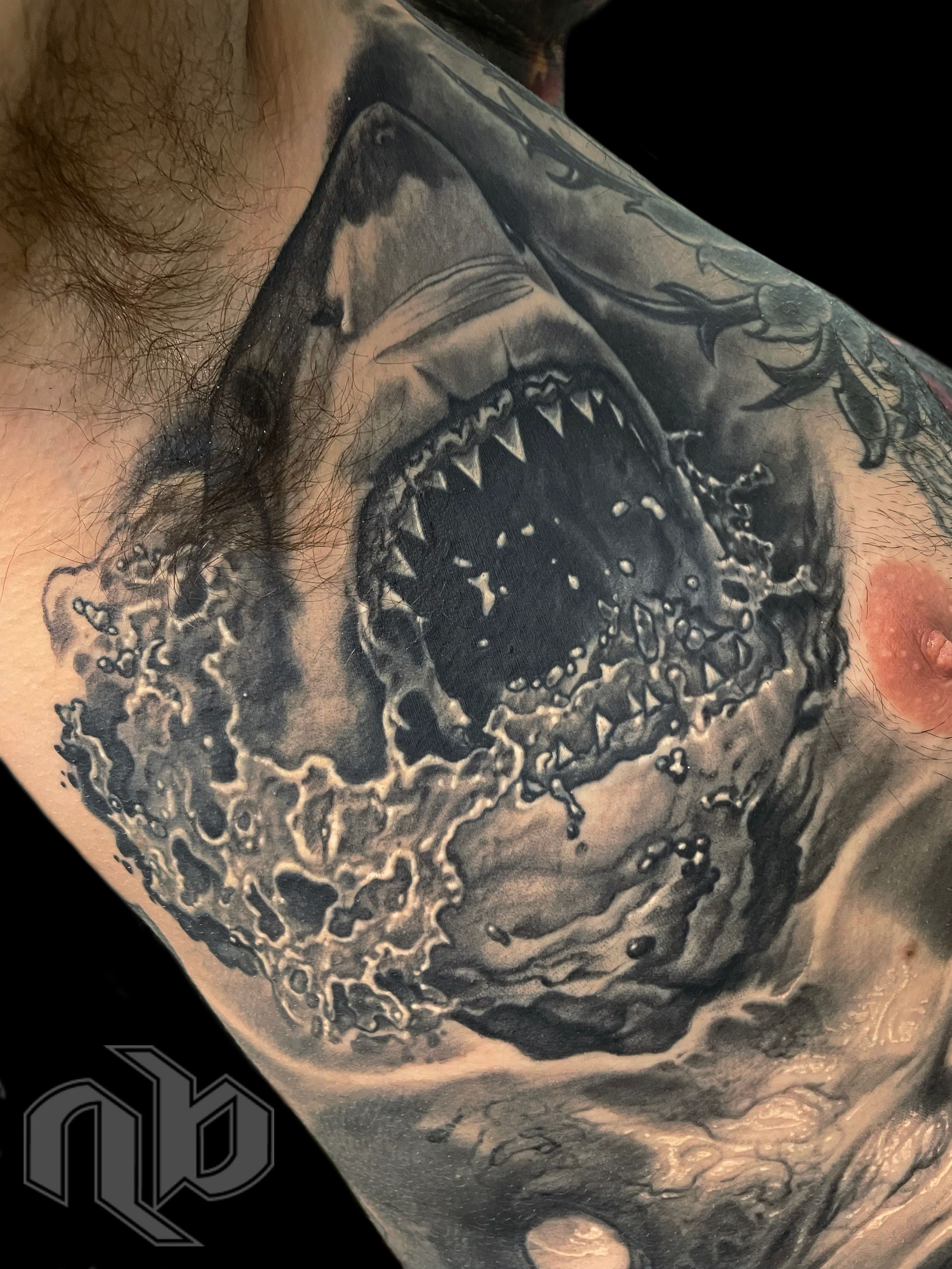 black and gray realism tattoo of great white shark with open mouth swimming out of the water surface with splashes by nick baxter in austin texas