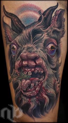 Medium leg tattoo of a horned goat head with bulging eyes, bared teeth, and a leafy twig clenched in its mouth.