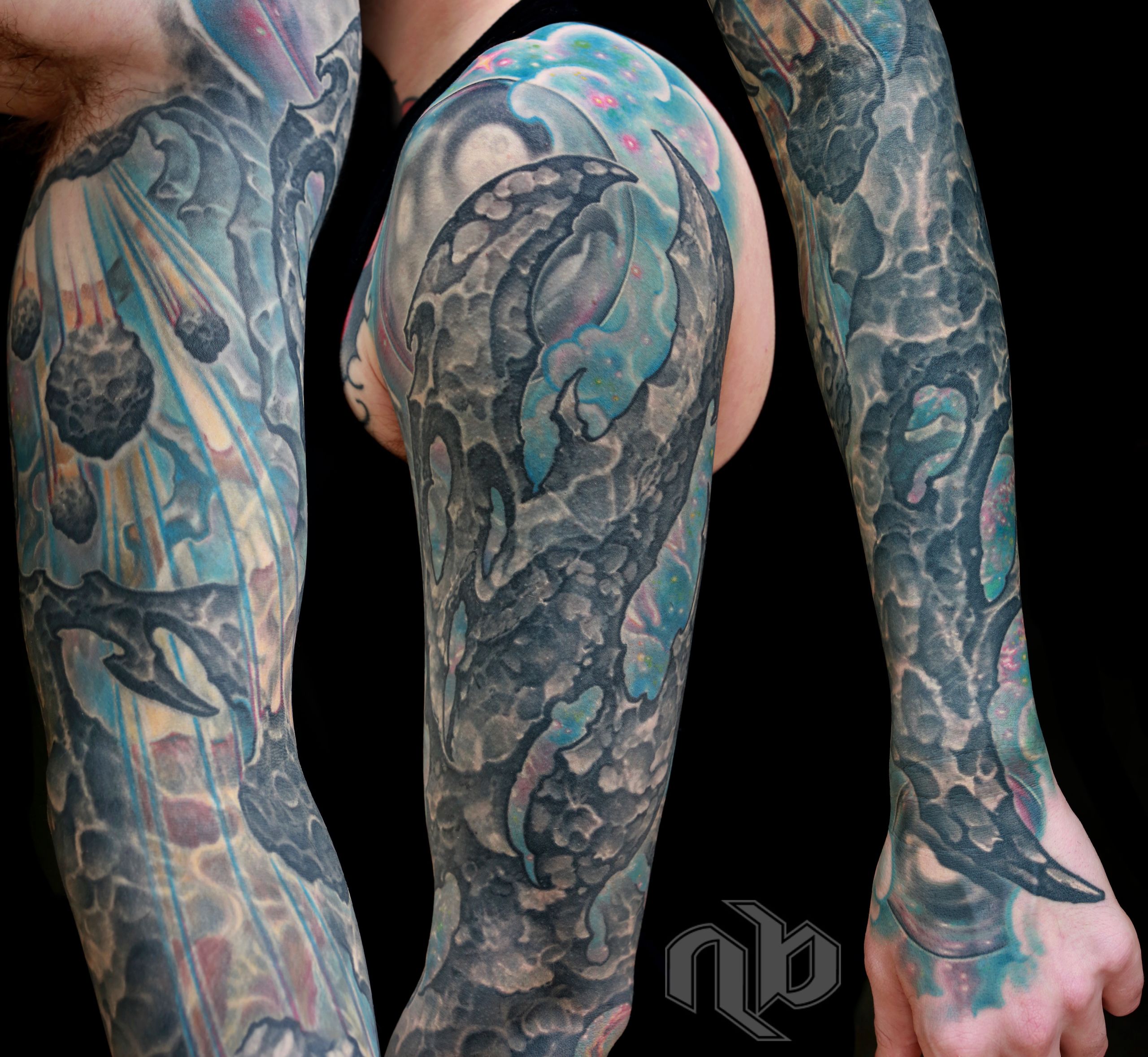 Three views show a large arm tattoo of dark bio-organic rocky forms, meteor-like rocks, and turquoise, pink, and yellow streaks.