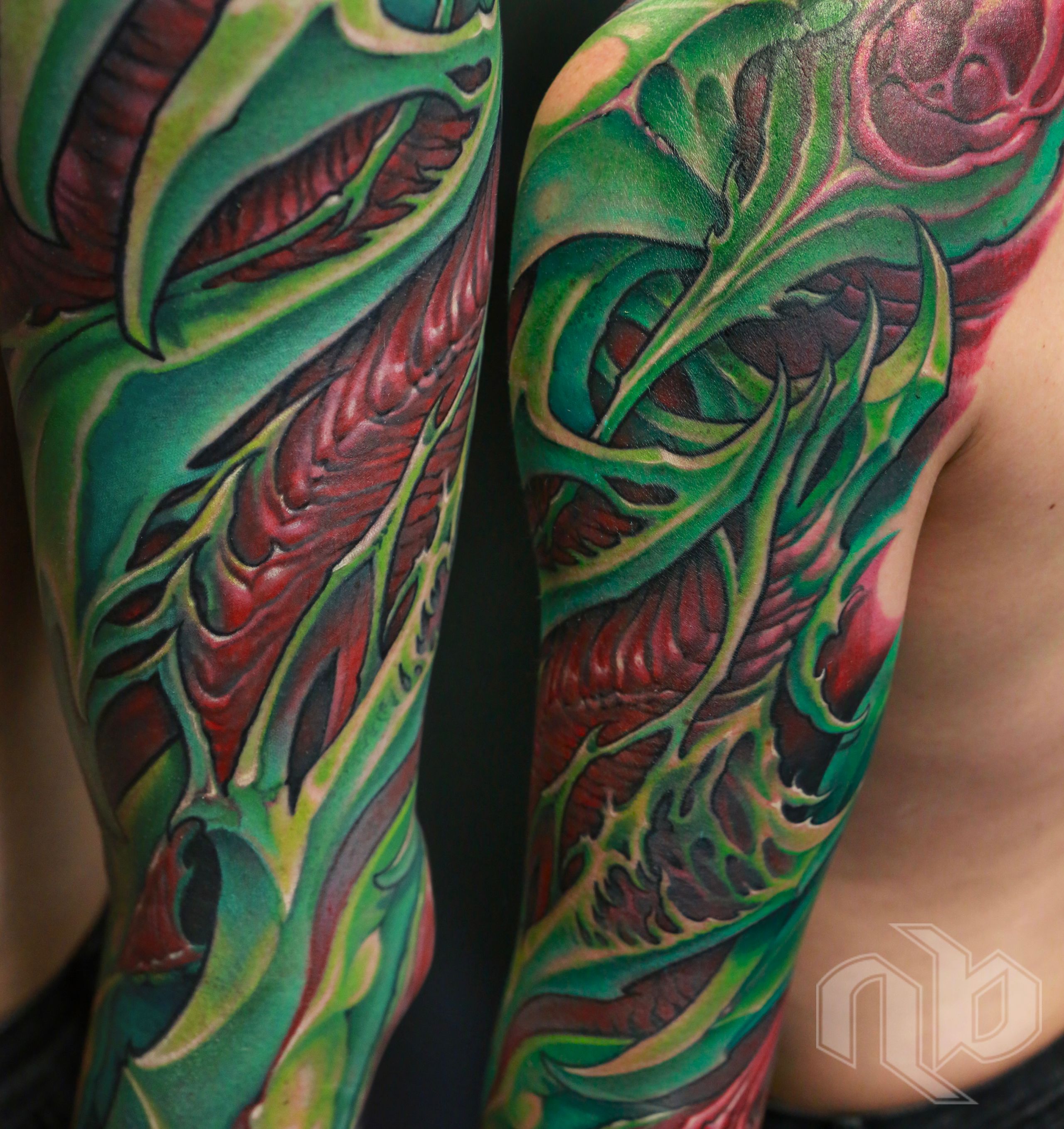 green and red bio organic sleeve tattoo inspired by parrot bird colors and shapes.