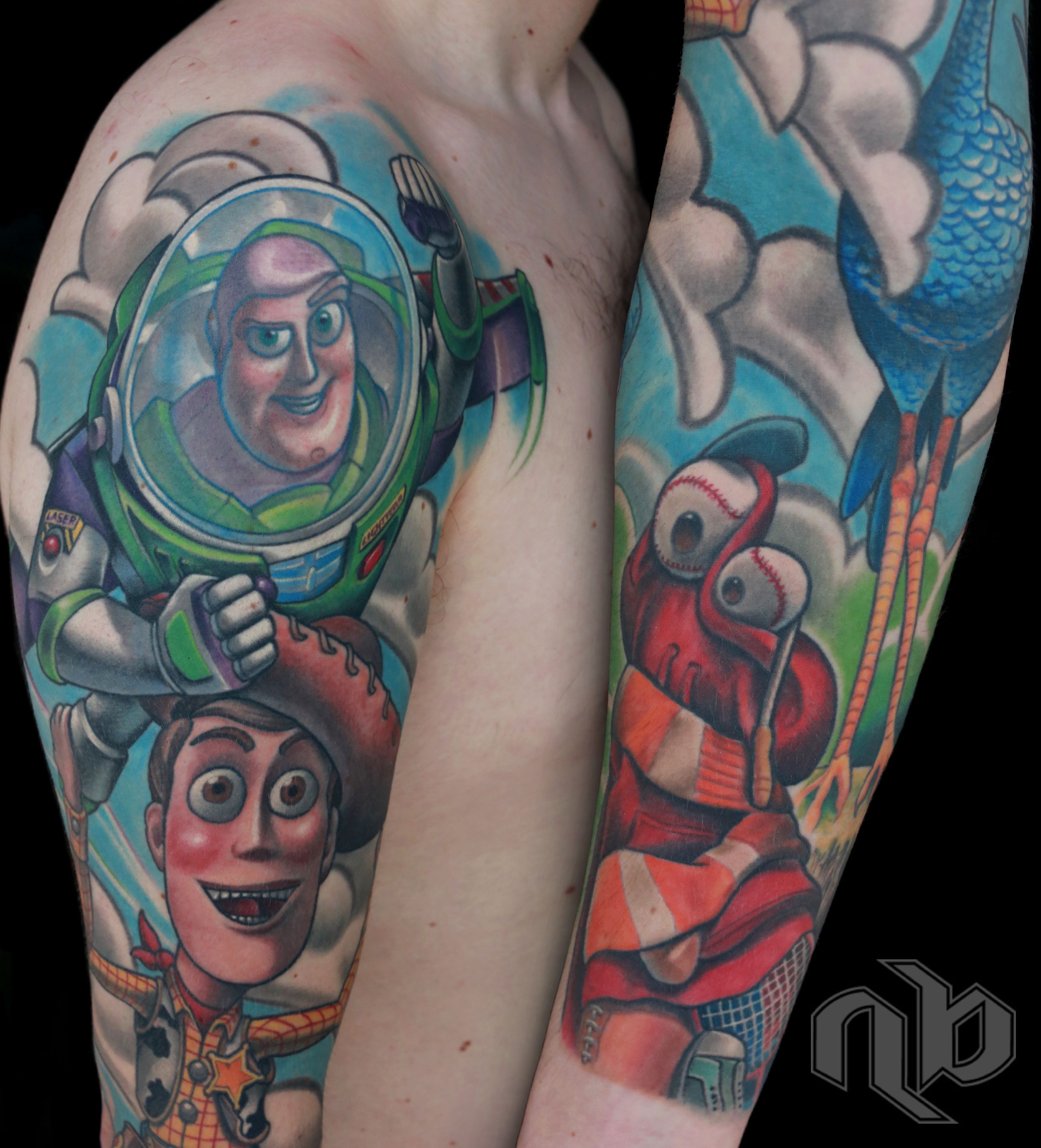 Side-by-side views of a large colourful arm tattoo featuring Buzz Lightyear, Woody, a blue bird, clouds, and a red baseball-eyed figure.