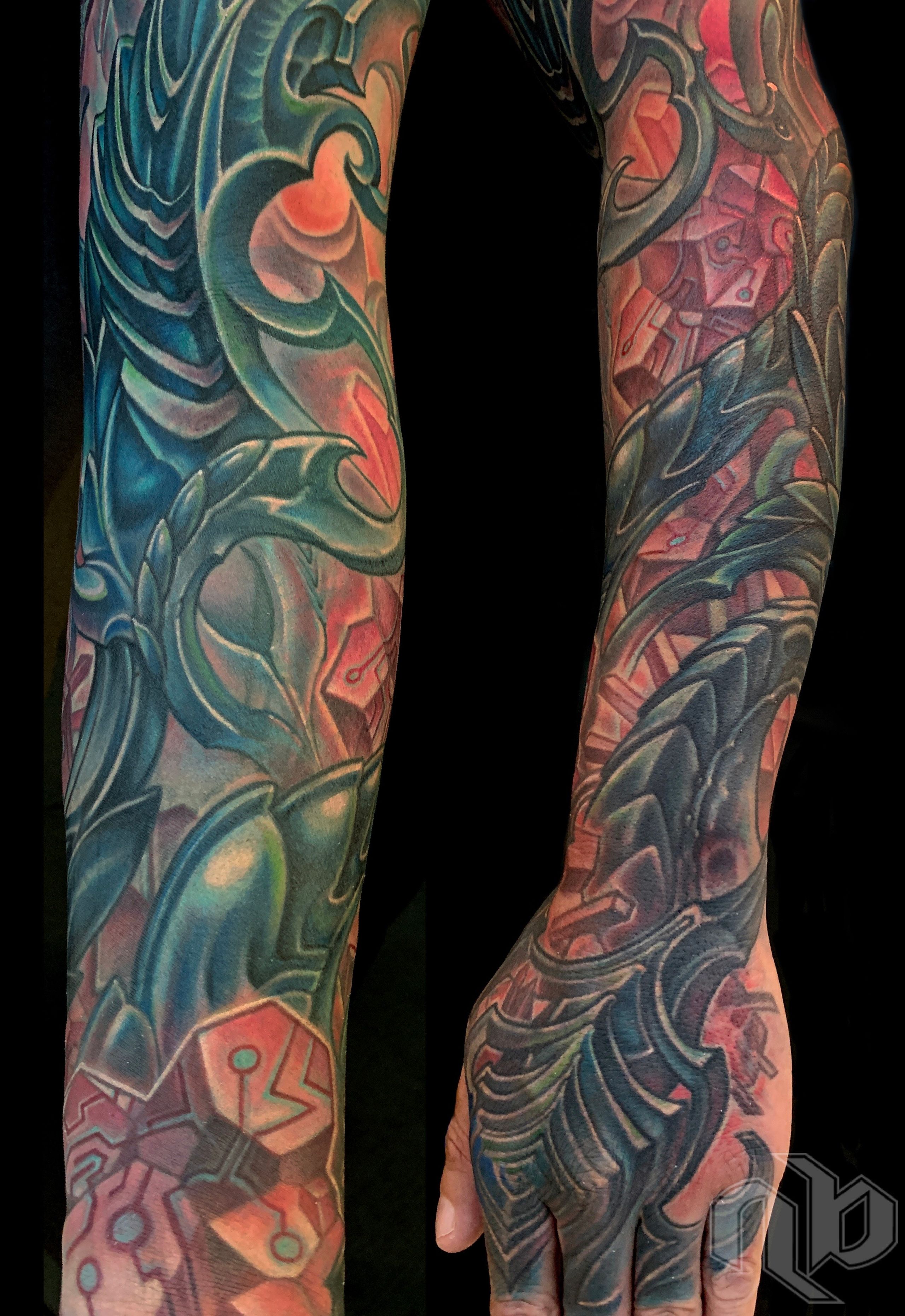 Two views show a large arm and hand tattoo of layered biomechanical forms in teal, blue, coral, pink, and purple.