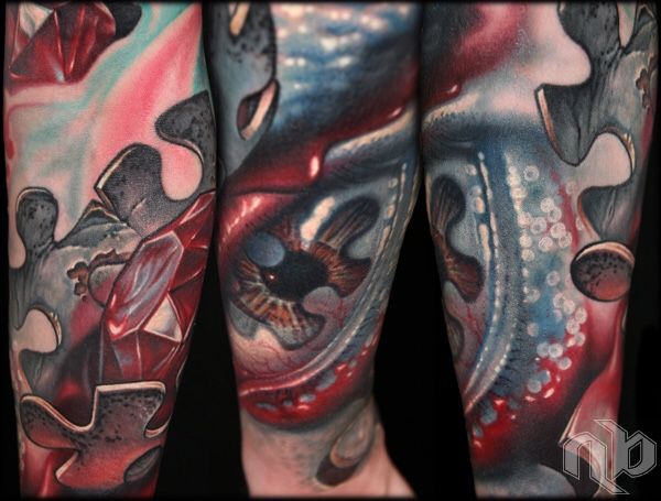 surreal color arm tattoo of puzzle piece with blood and human eye with red diamond by nick baxter in austin texas